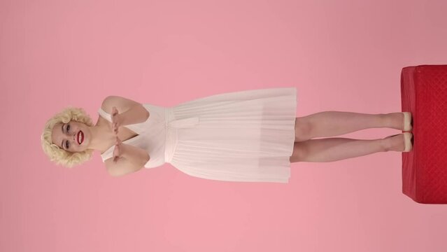 A woman brings her appreciation to you from the bottom of her heart, thanking you. Woman in the look of Marilyn Monroe standing full length on a red pedestal on a pink background. Vertical video.
