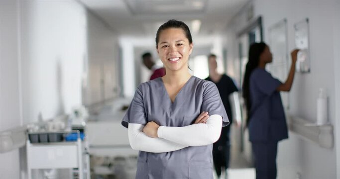 Portrait of happy asian female doctor wearing scrubs in hospital, slow motion