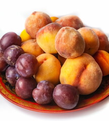 Naklejka na ściany i meble Peaches and plums on a ceramic plate close-up
