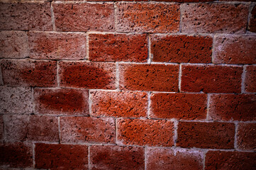 A close-up view of an intricate arrangement of red bricks, highlighting the rich textures and warm hues of these building materials. The repeating patterns and rugged surfaces of the bricks create 