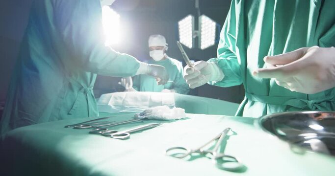 Diverse surgeons using surgical instruments in operating theatre at hospital, slow motion