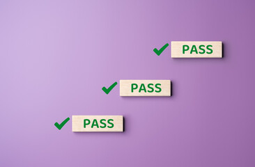 Wooden blocks with green check mark icon and word PASS on purple background. Industry quality and ISO standard, Task completion, Business goals achievement. Passing safety inspections in the factory.