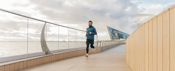 Full-length man warm-up in running shoes, correct technique beautiful running panorama. The trainer is a man active fitness every day outdoors.