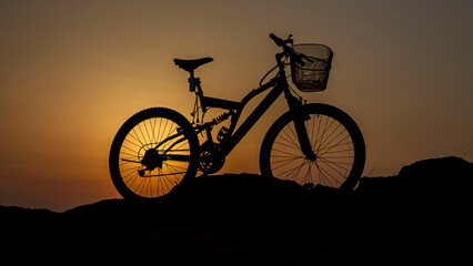 Silhouette of a bicycle with a basket on sunset during golden hour. 