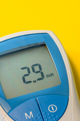 Self-measuring device with an INR (international normalized ratio) of 2.9 on a yellow background
