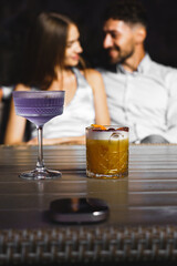 A couple in love drinks a cocktail and smokes a hookah on the terrace at night. Nightlife concept