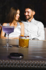 A couple in love drinks a cocktail and smokes a hookah on the terrace at night. Nightlife concept