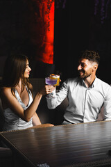 A couple in love drinks a cocktail and smokes a hookah on the terrace at night. Nightlife concept