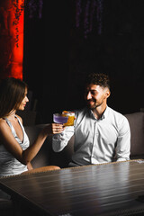 A couple in love drinks a cocktail and smokes a hookah on the terrace at night. Nightlife concept