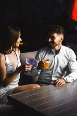 A couple in love drinks a cocktail and smokes a hookah on the terrace at night. Nightlife concept