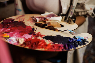 Partial shot of african american female artist holding painting palette and knife in studio, close...