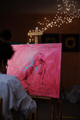 Painting on easel near blurred african american artist working in art studio with lighting