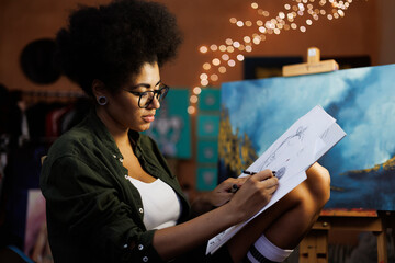 Young afican american female artist drawing sketches in art workshop
