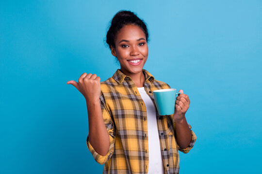 Photo portrait of pretty young girl hold red mug look dreamy empty space dressed trendy clothes isolated on blue color background