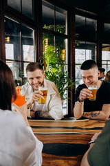 Happy group of friends drinking and clinking with beer and cocktails at brewery bar restaurant
