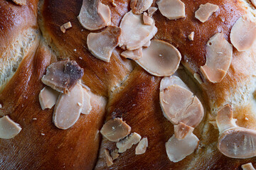 A macro shot of the surface of a Challah bread with roasted almond flakes.
