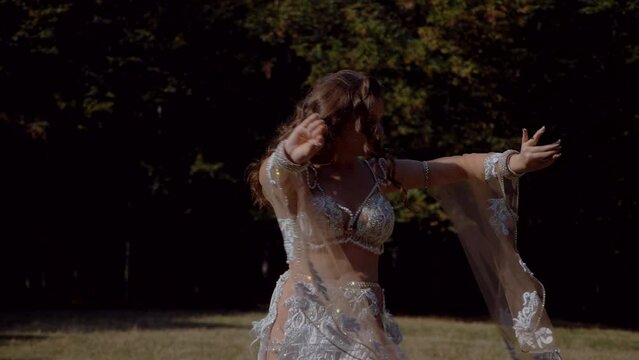 Girl belly dancing in the forest. Oriental dance. Beautiful dancer in bra and skirt.