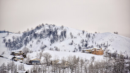 Distant view of village on hill in winter with white snow sitting on ground and houses