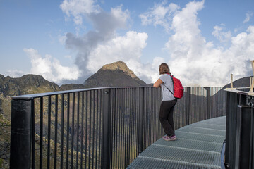 young curvy caucasian girl enjoying the views leaning on the railing of the tristaina solar viewpoint in Andorra