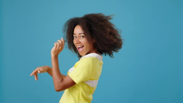 Happy African-American woman dances walking past on blue