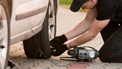 Man Inflates Tire With Portable Pump As Mechanic