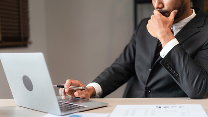 Businessman typing data on laptop while thinking and analyzing strategy of new startup business