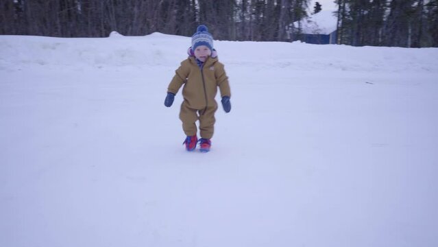 Boy Wearing Warm Clothing Walking On Snow Against Trees During Winter - Fairbanks, Alaska