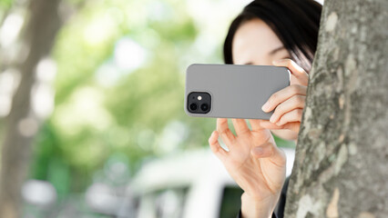 隠れてスマホで撮影する女性