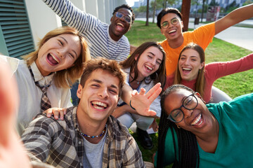 Happy group of multiethnic classmate taking a selfie outdoors in the university campus, looking at...