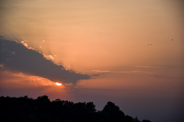 Sunset behind the clouds and mountain and forest view