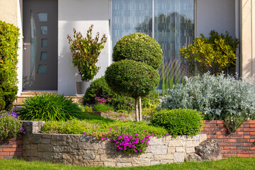 Aménagement de jardin paysagé, plante et fleur au pied d'une maison moderne. - obrazy, fototapety, plakaty