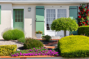 Fototapeta na wymiar Aménagement de jardin paysagé, plante et fleur au pied d'une maison moderne.