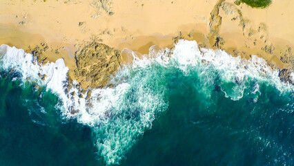 Aerial view of sea and rocks, ocean blue waves crashing on shore. Drone above of turquoise ocean...