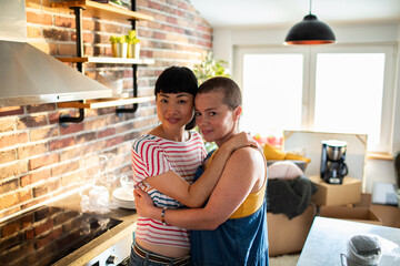 Portrait of a loving lesbian couple hugging in the kitchen