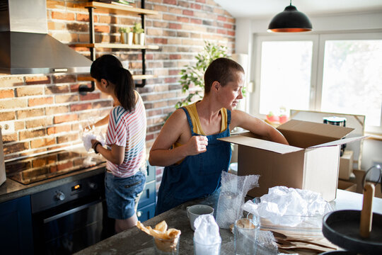 A lesbian couple unpacks kitchen items in their new home