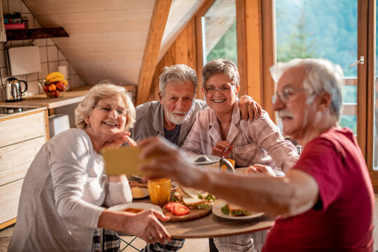 Group of elderly friends taking a selfie in their rented cabin in nature