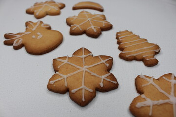 A white tablecloth filled with fresh homemade Christmas cookies in the shapes of snowflake,...