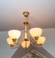 Chandelier with glass lampshades close-up on the background of the ceiling and wall of the room