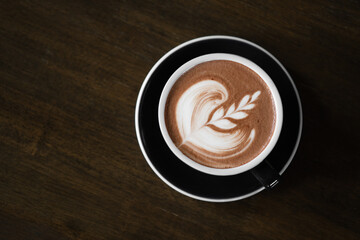 Top view of hot latte coffee or chocolate  with latte art in the cup on the wooden table. Cafe...