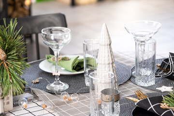 Serving a festive table with plates, forks, knives, napkins, glasses close-up in the modern interior of a loft house decorated for Christmas and New Year. Waiting for guests for a festive dinner