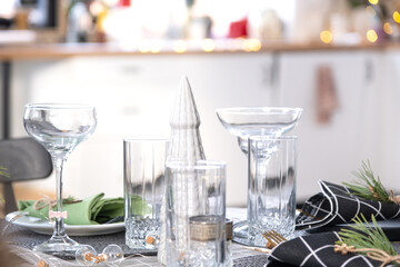 Serving a festive table with plates, forks, knives, napkins, glasses close-up in the modern interior of a loft house decorated for Christmas and New Year. Waiting for guests for a festive dinner