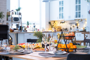 Serving a festive table with snacks, salads and goodies close-up in the modern interior of a loft house decorated for Christmas and New Year. Waiting for guests for a festive dinner