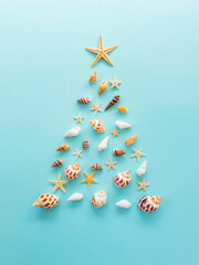 A Christmas tree made of shells and starfish is laid out on a blue background 