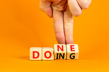 Doing and done symbol. Concept words Doing Done on wooden block. Beautiful orange table orange background. Businessman hand. Business doing and done concept. Copy space.