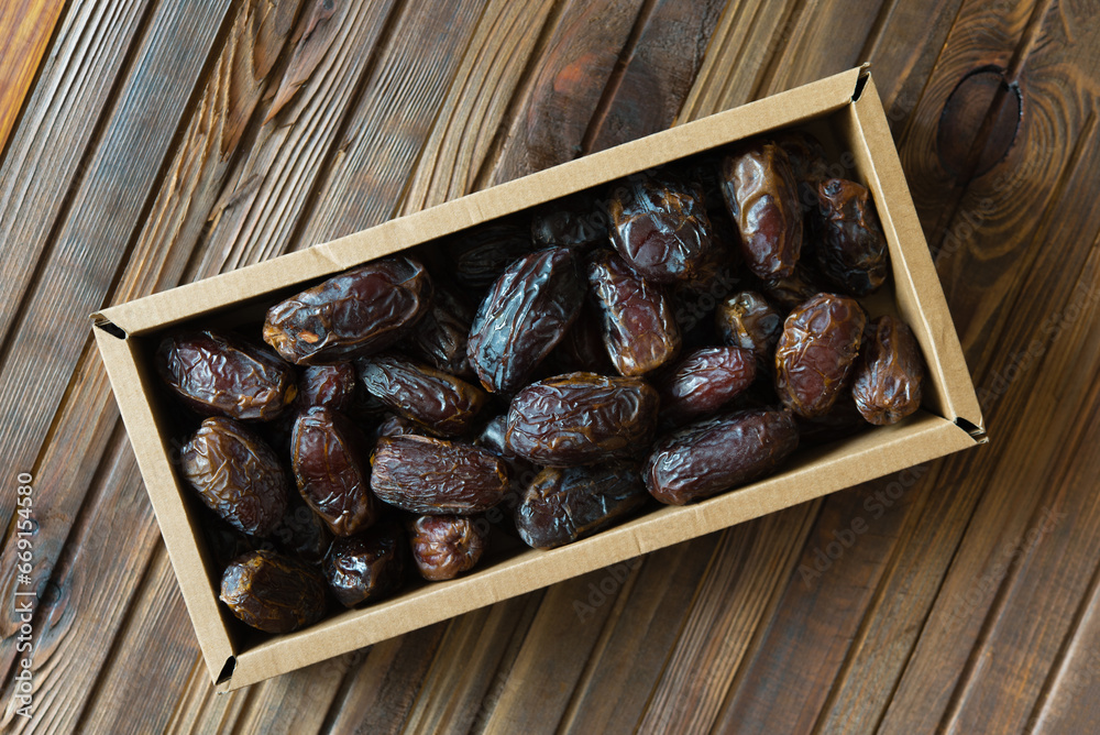 Wall mural Juicy dates on wooden table in a rectangular craft brown box, healthy snack. Dietary product, antidepressant.