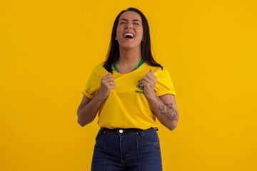 Young beautiful woman in shirt with the yellow color of Brazil in studio photo with various...