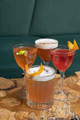 Four bright alcoholic cocktails in glasses on wooden cafeteria table