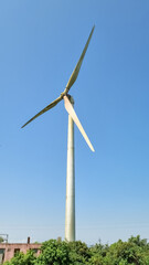 portrait full view of single wind turbine with blue clear sky