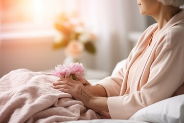 Senior woman holding a pink flower in a retirement home, closeup on hands - obrazy, fototapety, plakaty