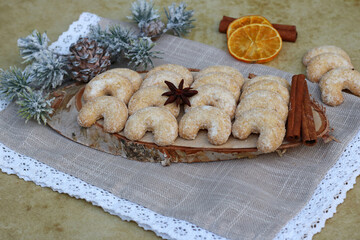 Fototapeta na wymiar Frisch gebackene Weihnachtsplätzchen, Vanillekipferl auf einer Holzscheibe. 